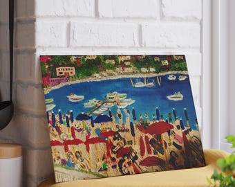 May include: A vibrant painting depicting a beach scene with people, boats, and umbrellas. The artwork showcases a blue sea, a sandy beach, and a town in the background. Red and blue umbrellas are scattered across the beach.