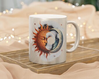 May include: A white ceramic mug with a celestial design. The mug features a sun and moon face, with the sun in orange and gold, and the moon in blue and grey. The mug is on a wooden tray.