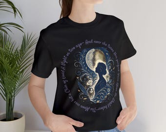May include: Black t-shirt with a circular design depicting a woman's silhouette, a moon, and floral details. The design includes text: "A Chin of Gold A Night or two ago - And now she turns Her perfect Face Upon the World below".
