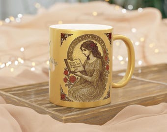 May include: A gold-coloured coffee mug with a handle, featuring an illustration of a woman reading a book, surrounded by roses. The mug has text on the side and is placed on a wooden tray.