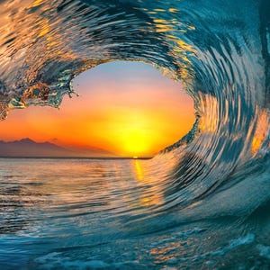 May include: A large wave breaks, revealing a vibrant orange and yellow sunset through the crest. The ocean is a deep blue, with the sun reflecting off the water.