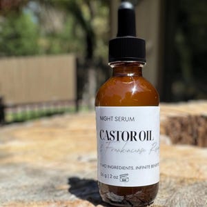May include: A brown glass bottle of night serum with a black dropper. The label reads "Castor Oil & Frankincense Resin". The bottle contains 2 oz (59 ml) of product and is marked with a 6M symbol.