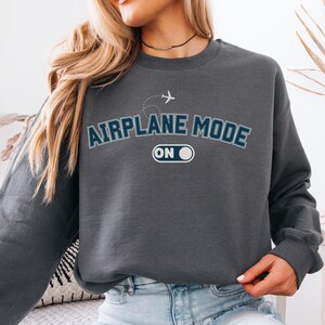 May include: A dark gray sweatshirt with the text "Airplane Mode On" in white and blue lettering. A small airplane icon is above the text.