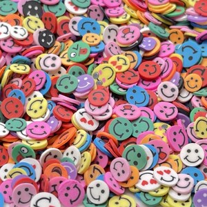 May include: A large assortment of colorful smiley face shaped resin embellishments. The embellishments are in various colors, including yellow, pink, blue, green, red, and orange.