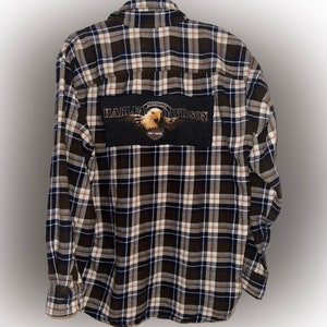 Może przedstawiać: Flanelowa koszula w czarno-białą kratę z naszywką Harley Davidson z orłem na plecach.