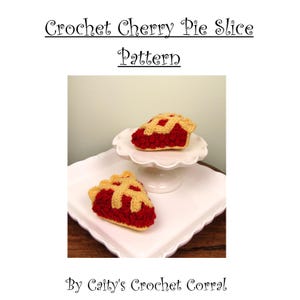 May include: Two crochet cherry pie slices with deep red filling and a light tan lattice crust. The text reads Crochet Cherry Pie Slice Pattern By Caity's Crochet Corral. The pie slices are displayed on a white scalloped pedestal and plate.