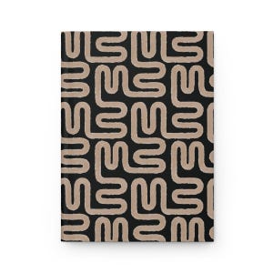 Puede incluir: Un cuaderno de tapa dura cerrado con un fondo negro y un patr&oacute;n repetitivo de formas abstractas beige. El cuaderno tiene un dise&ntilde;o moderno, adecuado para escribir o dibujar.