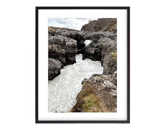 May include: A close-up of a rushing river flowing through a narrow canyon formed by dark gray rock formations.