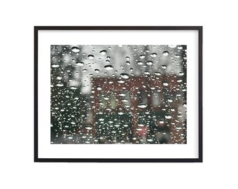 May include: A blurry image of a building seen through a window covered in raindrops.