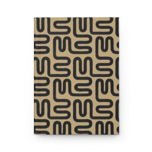 Puede incluir: Un cuaderno rectangular con una cubierta beige que presenta un patr&oacute;n repetitivo de formas abstractas gruesas y negras. Las formas se asemejan a la letra "L" y est&aacute;n dispuestas en un dise&ntilde;o de cuadr&iacute;cula. El cuaderno est&aacute; cerrado.