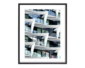 May include: A photograph of a modern building with a geometric pattern of balconies and windows. The balconies are white and the windows are blue and green.