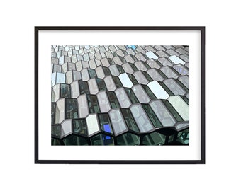 May include: A close-up of a building facade with a geometric pattern of hexagonal windows. The windows are made of glass and have a reflective surface. The building is made of concrete and has a modern design.