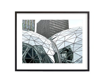 May include: A black and white photograph of a modern glass building with a geometric pattern. The building is made up of many small, triangular pieces of glass. The building is surrounded by other buildings, which are also made of glass.