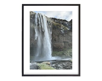 May include: A powerful waterfall cascades down a rocky cliff face, creating a misty spray. Lush green vegetation surrounds the base of the waterfall, adding a touch of vibrancy to the scene.