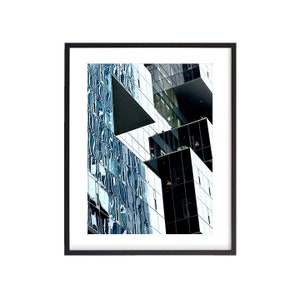Peut inclure: Un immeuble moderne au design géométrique, avec un mélange de panneaux de verre noir et bleu. Le bâtiment a une forme angulaire unique, créant une impression de profondeur et de dimension.