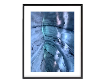 May include: A close-up view of a blue ice cave with a narrow opening at the bottom. The ice is textured and has a light blue hue. The cave is lit by natural light, creating a dramatic effect.