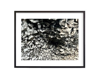 May include: A close-up of a black and white rock formation with a cave-like opening in the center.