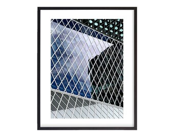May include: A close-up of a building with a diamond-shaped pattern on the windows. The windows are reflecting the sky and other buildings. The building is made of glass and metal.