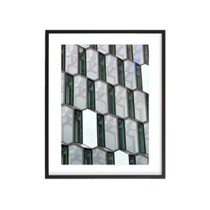 Puede incluir: Primer plano de un edificio moderno con un patrón de ventanas en forma de panal. Las ventanas son de vidrio y reflejan el cielo y las nubes. El edificio está hecho de hormigón blanco y tiene un diseño moderno y elegante.