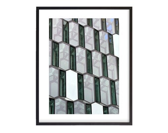 May include: A close-up of a modern building with a honeycomb pattern of windows. The windows are made of glass and reflect the sky and clouds. The building is made of white concrete and has a sleek, modern design.