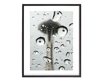 May include: A black and white photograph of the Space Needle in Seattle, Washington, seen through a window covered in raindrops.