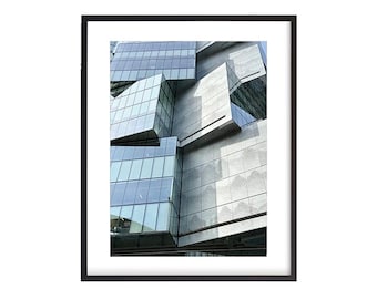 May include: A modern building with a geometric design featuring large windows and gray concrete panels.