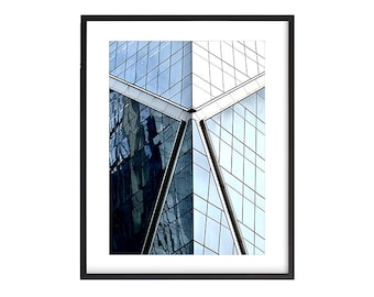 May include: A close-up of a modern building with a geometric glass facade. The glass panels are arranged in a grid pattern, creating a sense of depth and perspective. The building is reflected in the glass, creating a sense of symmetry and repetition.