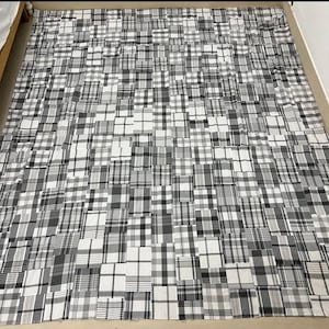 May include: A large, patchwork quilt featuring a repeating pattern of black, white, and gray plaid squares. The quilt is made of various sizes of squares, creating a textured and visually interesting design. The overall aesthetic is neutral and versatile.