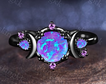 May include: Black ring with a large iridescent opal gemstone surrounded by smaller purple gemstones and three crescent moon designs.