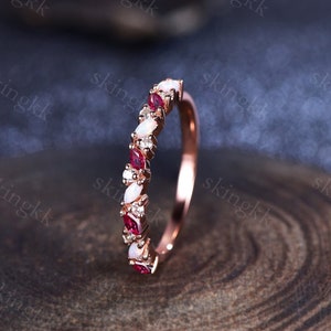Peut inclure: Une bague de fiançailles en or rose avec des opales blanches ovales et des rubis rouges alternés.