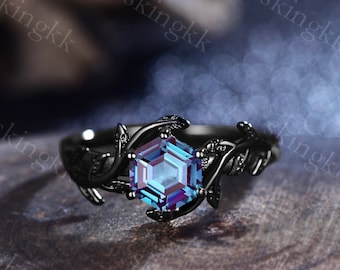 May include: A black ring with a hexagonal blue gemstone set in a vine-like design.