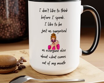 May include: White ceramic coffee mug with a black rim and handle. The mug features a colorful illustration of a woman with her hands over her mouth and the text "I don't like to think before I speak. I like to be just as surprised as everyone else about what comes out of my mouth."