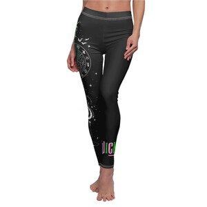 May include: Black leggings with a white celestial design on the left leg, including a zodiac wheel, bats, and stars. The word "Juicy" is printed in green and pink near the ankle. The leggings have a white waistband.