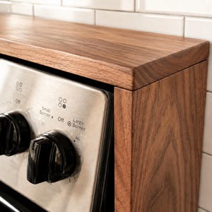 Handmade walnut stove top organizer shelf with adjustable size for different stove lengths and back panel heights ideal for creating extra kitchen storage and displaying spices oils jars and cooking supplies in a clean stylish way