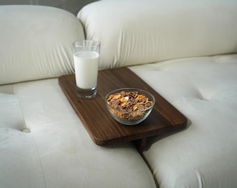 May include: A wooden tray with a bowl of cereal and a glass of milk on a white couch. The tray is designed to be used on a couch or bed.