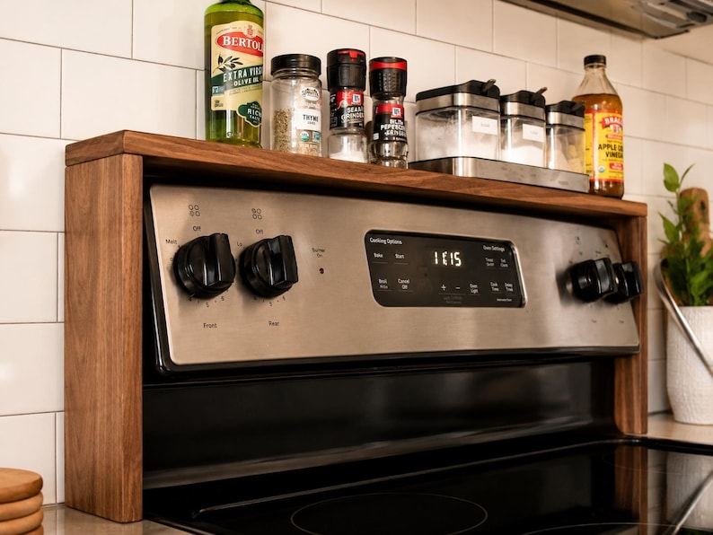 Custom walnut kitchen storage shelf designed to sit above the stove back panel and provide space for spices oils vinegar jars and small decor a practical wooden organizer for a cleaner more organized cooking area