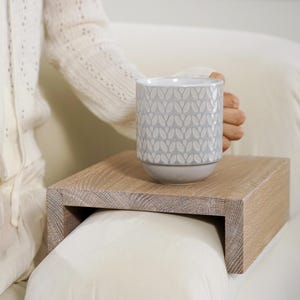 Sofa arm table crafted from white oak fits snugly over the couch armrest creating a practical flat surface for holding everyday items such as drinks snacks or remotes this compact wood side table is ideal for small apartments or minimalist homes offering style and convenience in one piece