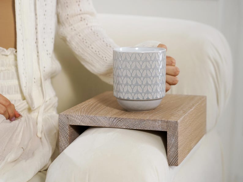 Sofa arm table crafted from white oak fits snugly over the couch armrest creating a practical flat surface for holding everyday items such as drinks snacks or remotes this compact wood side table is ideal for small apartments or minimalist homes offering style and convenience in one piece