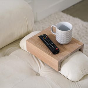 White oak sofa side table designed to rest securely on the arm of a couch or sofa provides a stable surface for holding drinks snacks remotes or phones this wood armrest tray table also functions as a compact side table ideal for small living rooms apartments and minimalist spaces