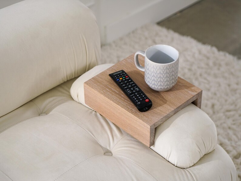 White oak sofa side table designed to rest securely on the arm of a couch or sofa provides a stable surface for holding drinks snacks remotes or phones this wood armrest tray table also functions as a compact side table ideal for small living rooms apartments and minimalist spaces