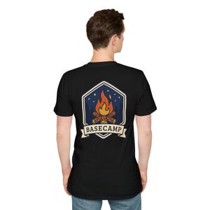 Puede incluir: Camiseta negra con un gráfico de una fogata dentro de un hexágono azul y blanco. La fogata tiene llamas naranjas y amarillas, con la palabra "BASECAMP" en una pancarta debajo.