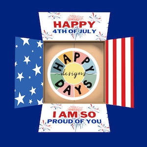 Puede incluir: Una caja de regalo roja, blanca y azul con un tema patriótico. La caja está abierta y muestra una rueda colorida con las palabras "Happy Days" y "designs" escritas en ella. La parte superior de la caja dice "Happy 4th of July" y la parte inferior dice "I am so proud of you".