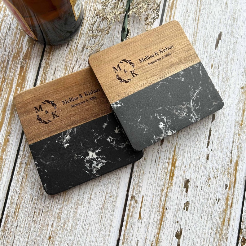 Pu&ograve; includere: Due sottobicchieri quadrati in legno con un design in marmo bianco e nero. La met&agrave; superiore di ogni sottobicchiere &egrave; in legno con il testo "M & K" in una ghirlanda, "Mellisa & Kishan" e "September 9, 2023" inciso.