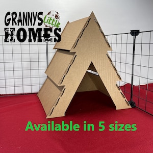 May include: A cardboard house for small pets, like guinea pigs or hamsters. The house is shaped like a triangle with a small opening at the bottom. The house is made of brown cardboard and has a textured surface. The house is sitting on a red surface. The text "Granny's Little Homes" is visible in the top left corner of the image. The text "Available in 5 sizes" is visible in the bottom center of the image.