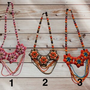 May include: Three beaded necklaces with flower designs. The first necklace is pink and white, the second is orange and brown, and the third is blue, orange, and red. The necklaces are numbered 1, 2, and 3.