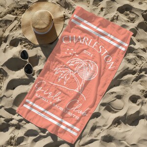 Puede incluir: Una toalla de playa de color rosa coral con rayas blancas y el texto "Charleston 2021" y "Girls Club Rachel's Bachelorette" impreso en ella. La toalla presenta un gr&aacute;fico de palmera y sol.
