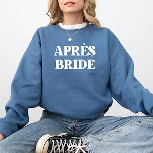 Könnte beinhalten: Ein blaues Sweatshirt mit dem Text "APRÈS BRIDE" in weißen Buchstaben.