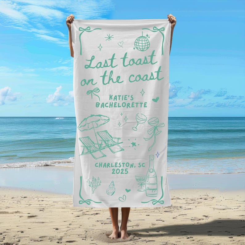 May include: White beach towel with a green design that says "Last toast on the coast" with a beach chair, umbrella, and champagne bottle illustration. The text also says "Katie's Bachelorette, Charleston, SC 2025".
