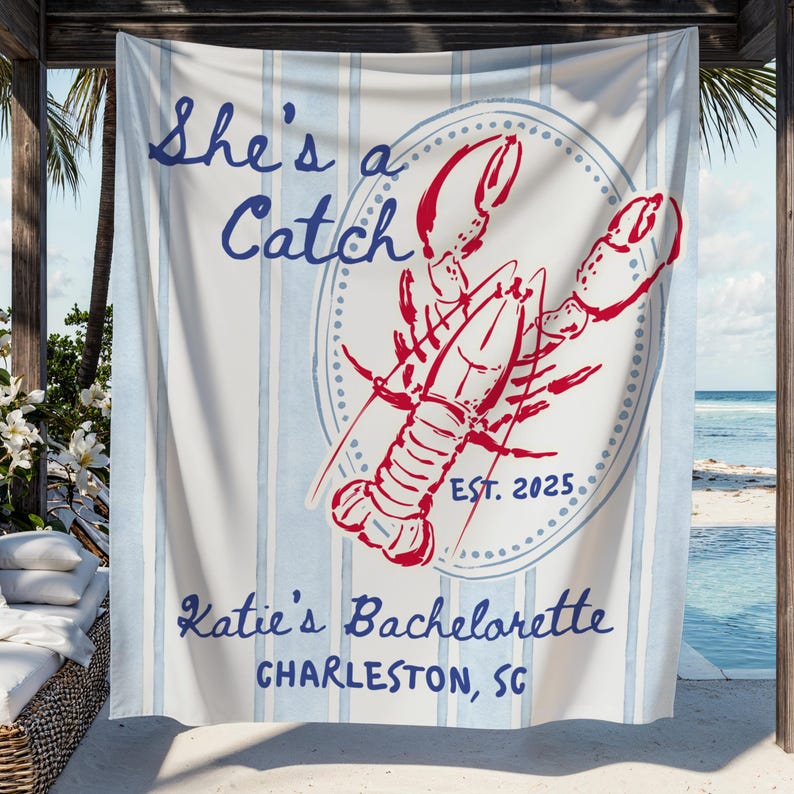 May include: A beach towel with blue and white stripes and the text "She's a Catch" in blue script. A red lobster graphic is centered, with "EST. 2025" below. The text "Katie's Bachelorette, Charleston, SC" is at the bottom.