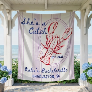 May include: A white and lavender striped banner with the text "She's a Catch" and "Katie's Bachelorette Charleston, SC". A red lobster graphic is in the center, with "EST. 2025". The banner is hanging outdoors.